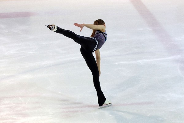 Figure skater graciously gliding over ice, arabesque spiral