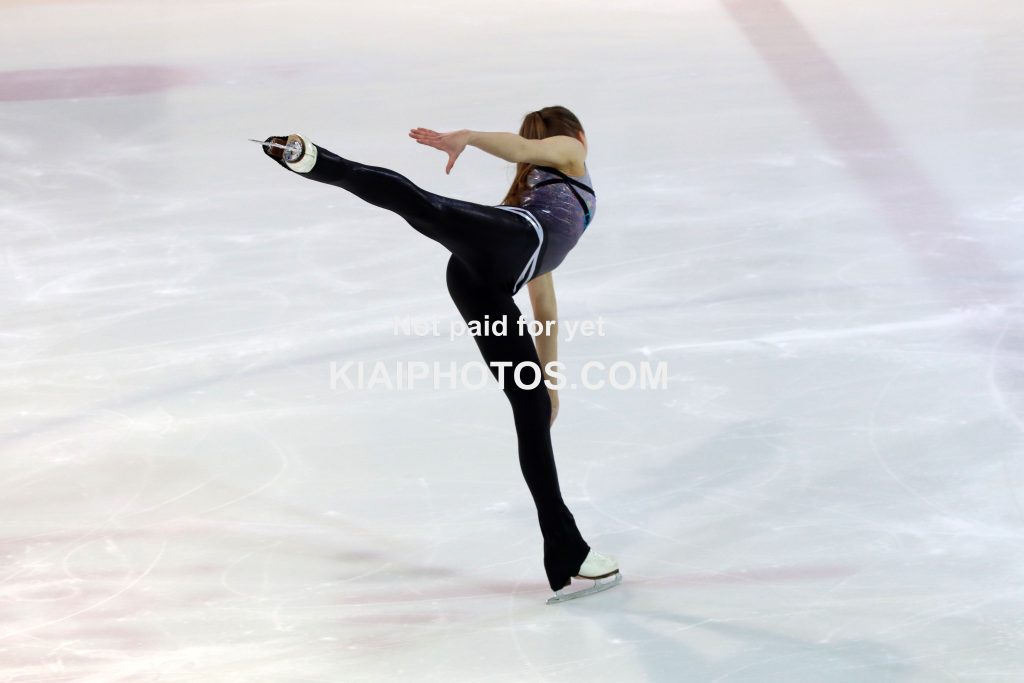 Figure skater graciously gliding over ice, arabesque spiral